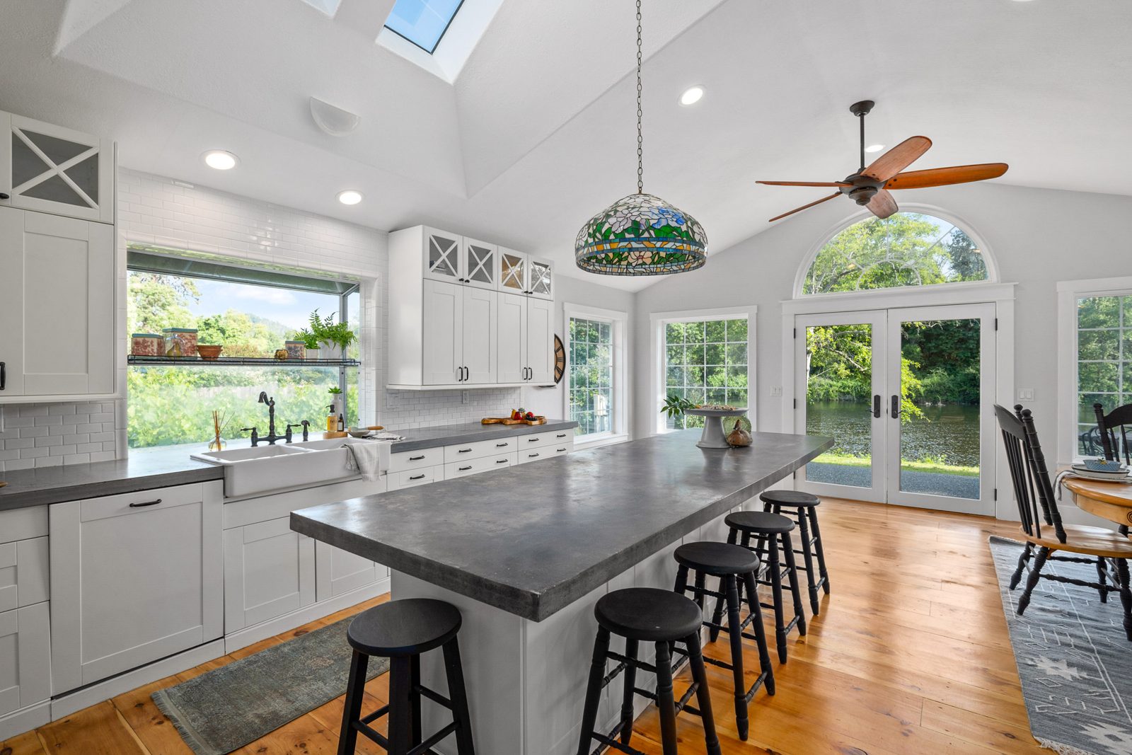 Kitchen with a concrete-topped island, farmhouse sink, skylights, and French doors to the backyard