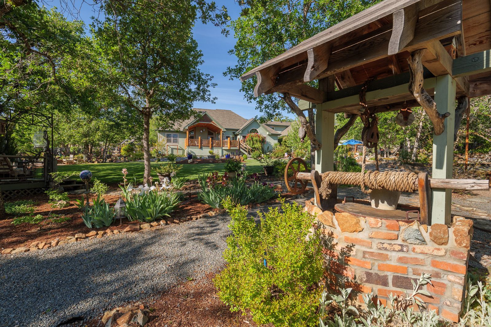 Brick-and-stone wellhead with a rope windlass in the garden of a rural Southern Oregon home