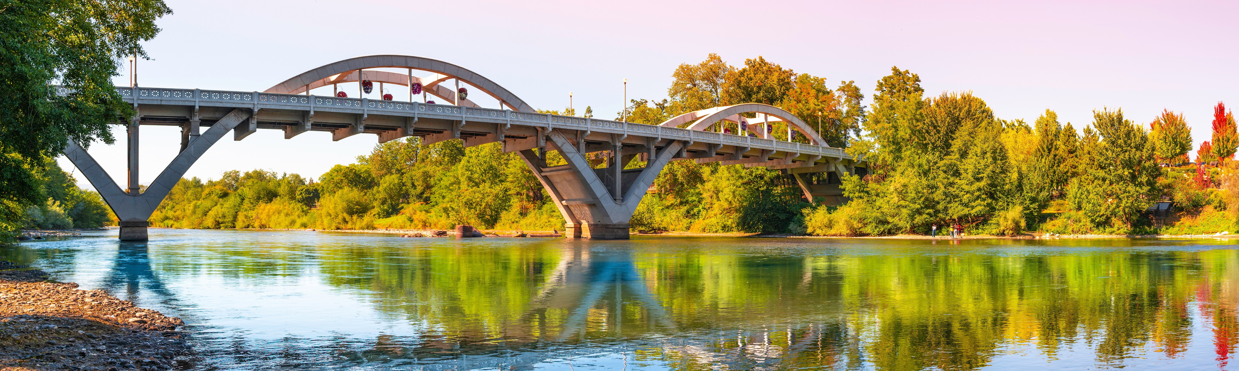 The Caveman Bridge over the Rogue River in Grants Pass, Oregon, reflected in the water on a fall evening